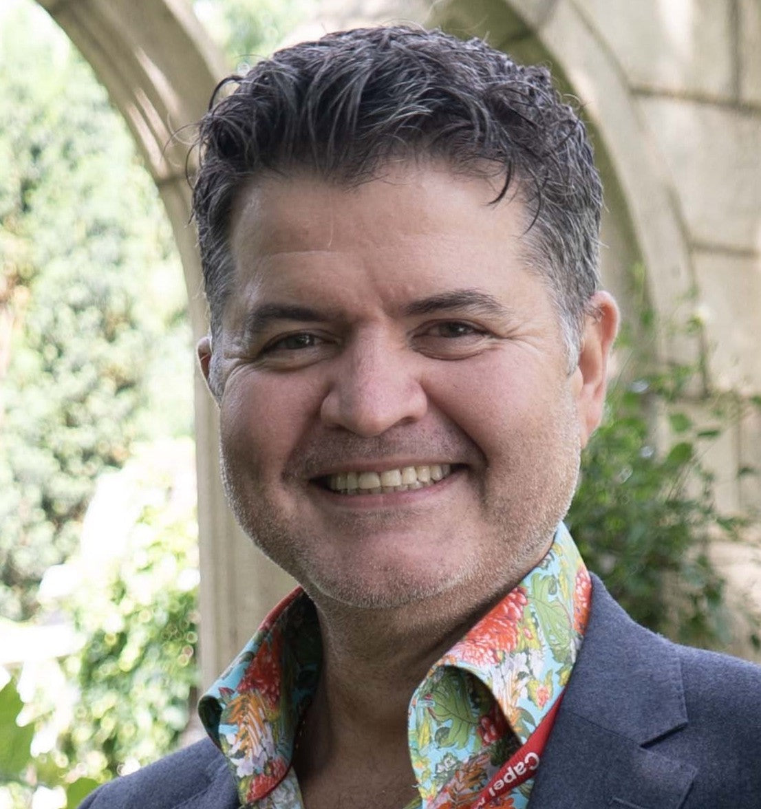 Nico, the founder of UNA, is wearing a colourful shirt with a blurred outdoor background