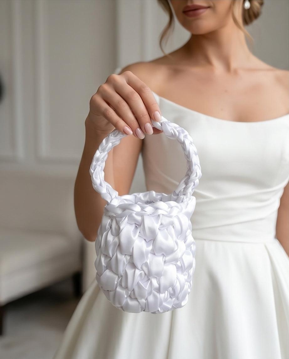 Woman in a white WEDDING dress holding a white SATIN CROCHET handbag against a neutral background