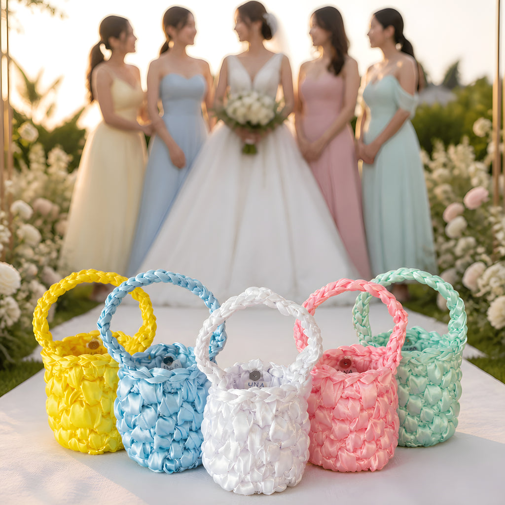 Five colorful SATIN CROCHET BAGs on a table with women in pastel dresses in the background.