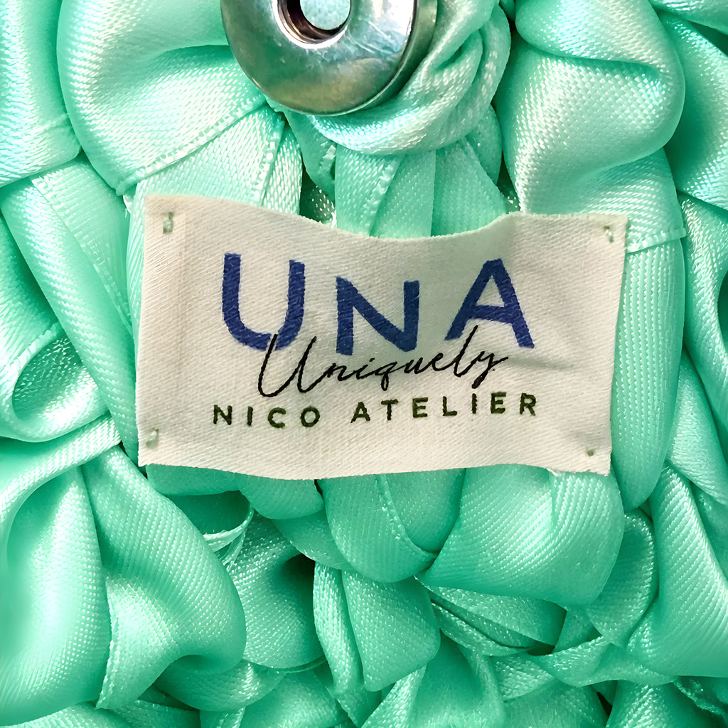 Close-up of mint green SATIN CROCHET BAG with a 'UNA uniquely NICO ATELIER' label.